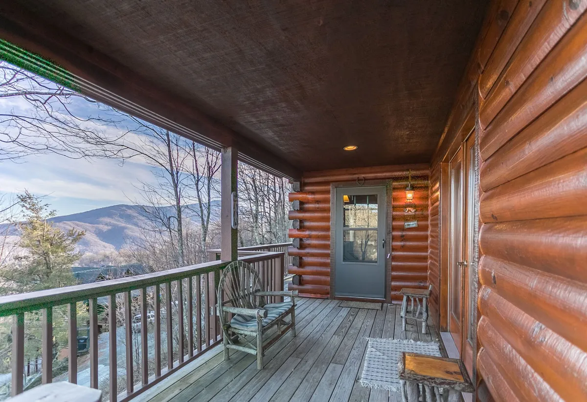 This exterior image shows a classic wooden rocking chair set on the porch of a log cabin, with a breathtaking view of the surrounding mountains in the background. The scene is tranquil and open, evoking the feeling of being immersed in nature and the high-altitude environment.