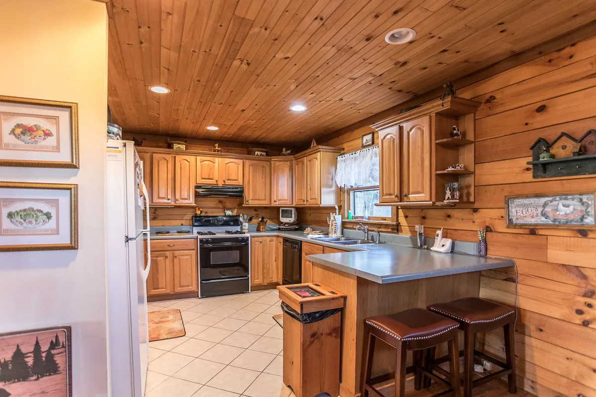 This image captures a well-equipped kitchen with wooden cabinetry, a central island with stools, and modern appliances. The space feels inviting and practical, perfect for both cooking feasts and quick snacks.